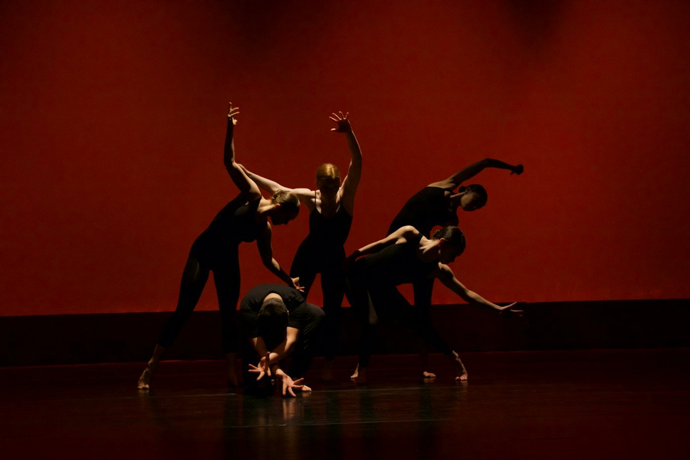 Groupe de danseurs en silhouette sur un plateau baigné de lumière rouge